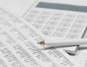 Documents comptables avec tableau de chiffres, calculatrice et stylo, illustrant l’importance de bien conserver ses données financières.